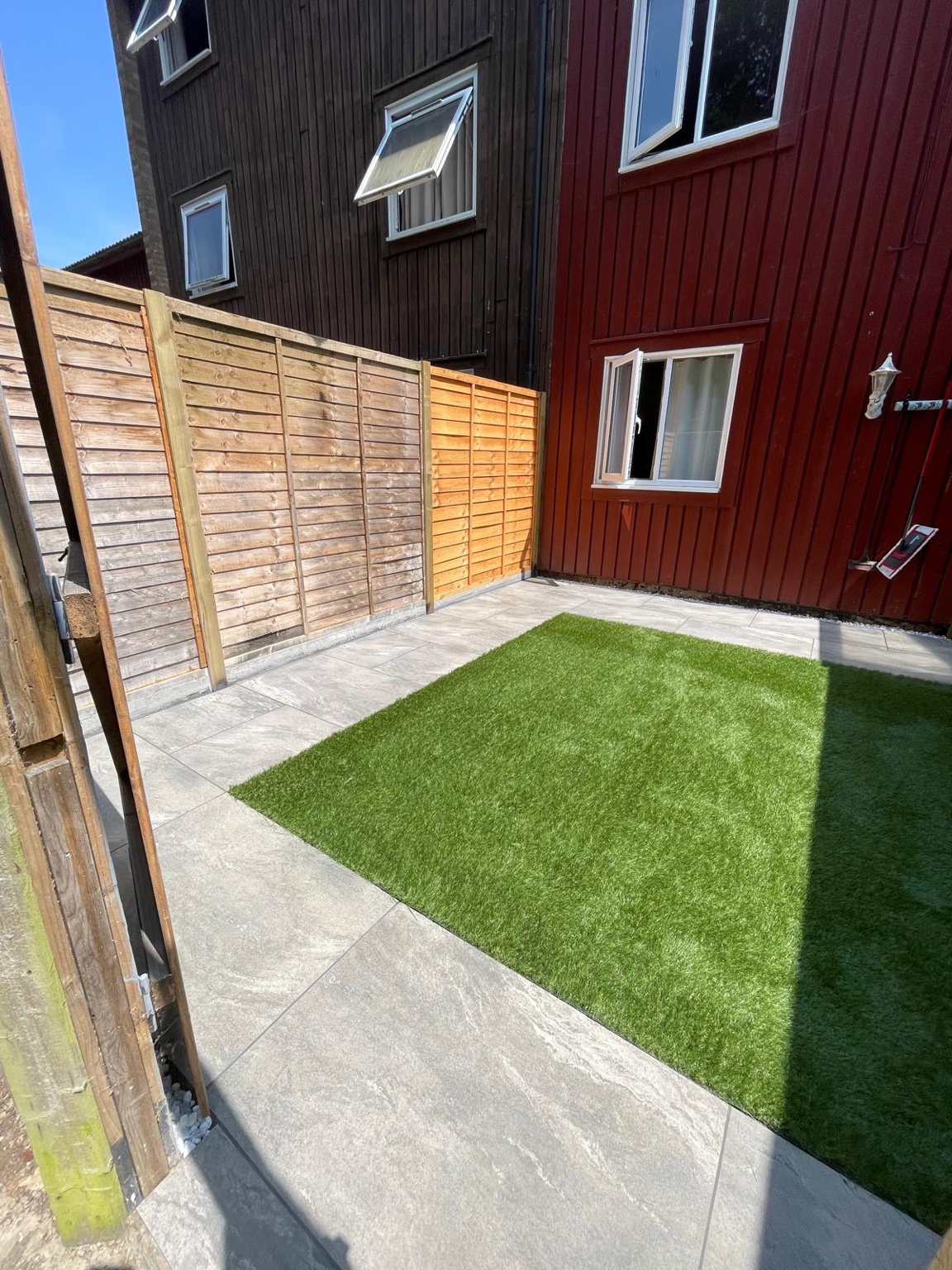 Paved path and artificial grass beside timber fencing