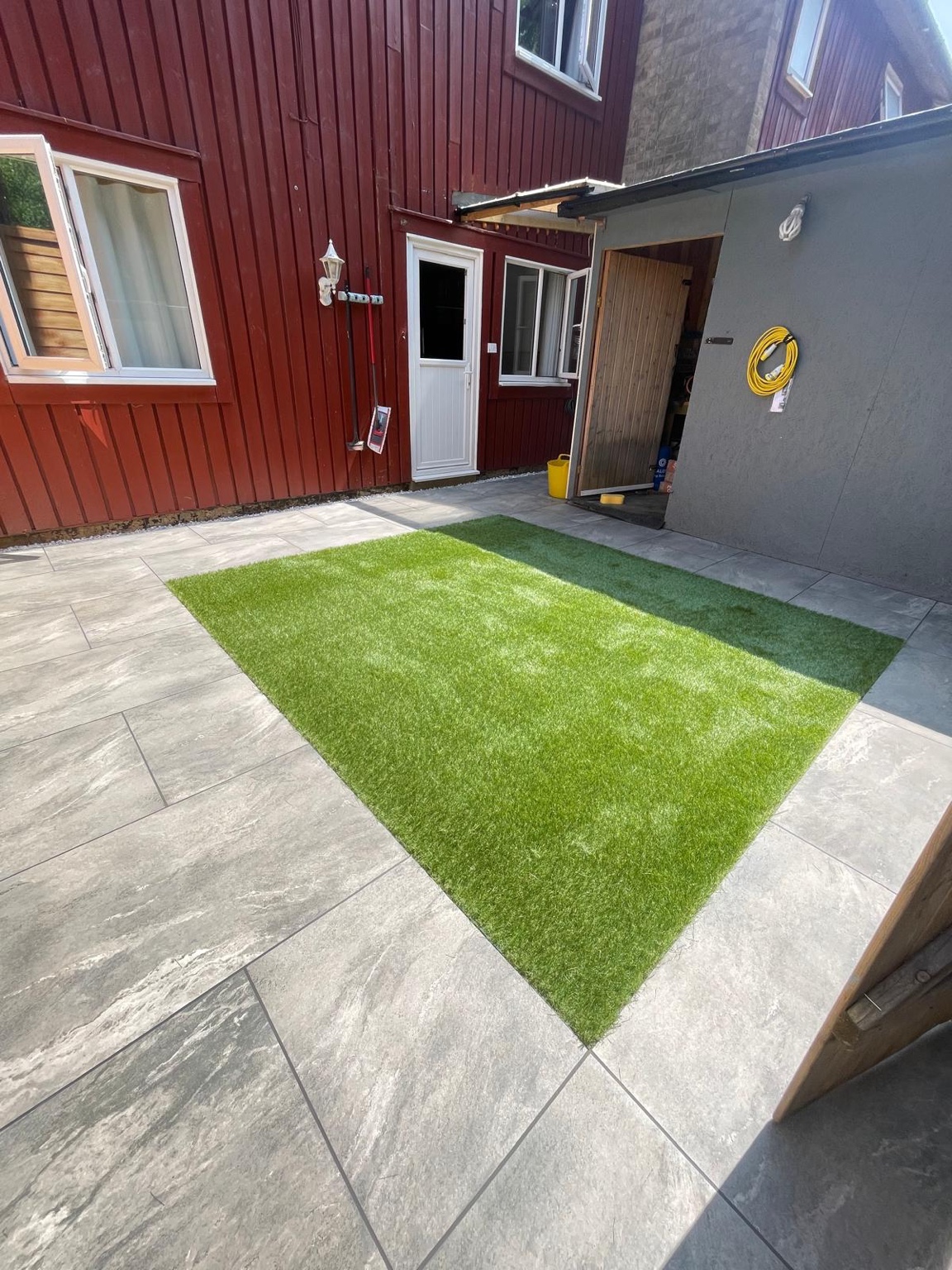 View of the finished paving and artificial grass from the side of the courtyard