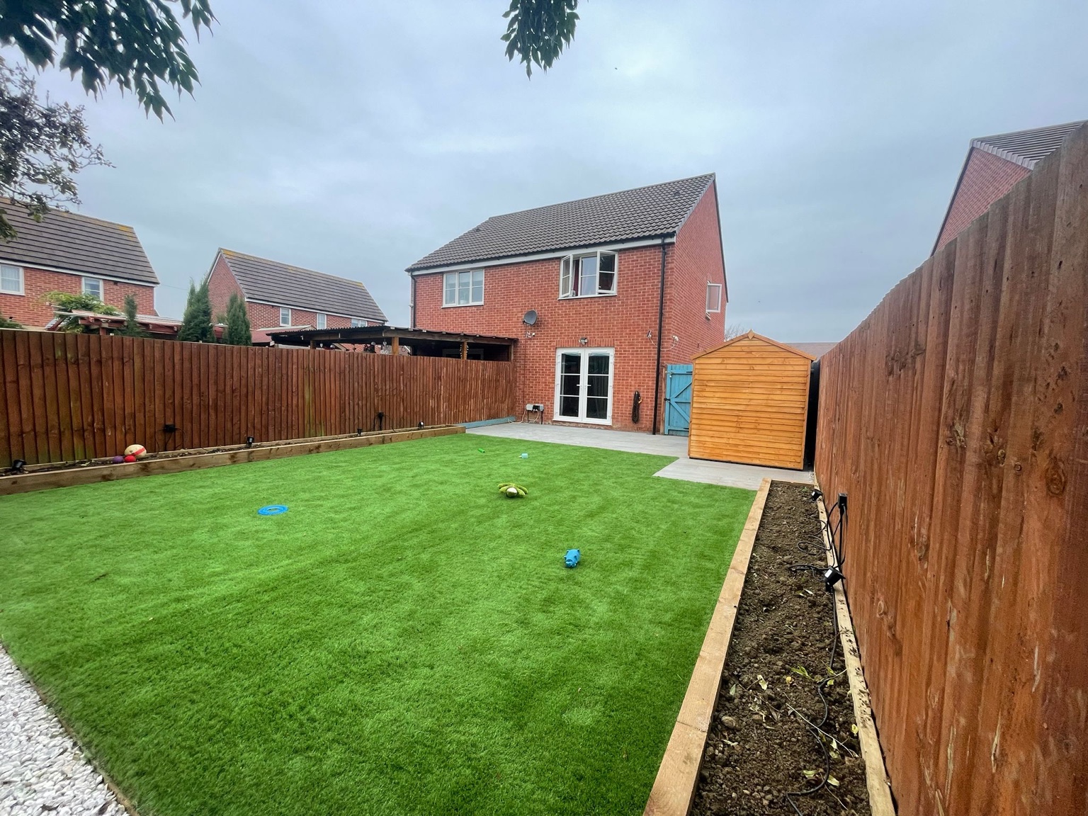 Green lawn framed by timber raised beds and fencing