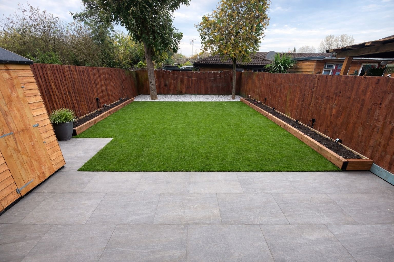 Wide view of the landscaped garden with a paved patio, lawn and raised planting beds