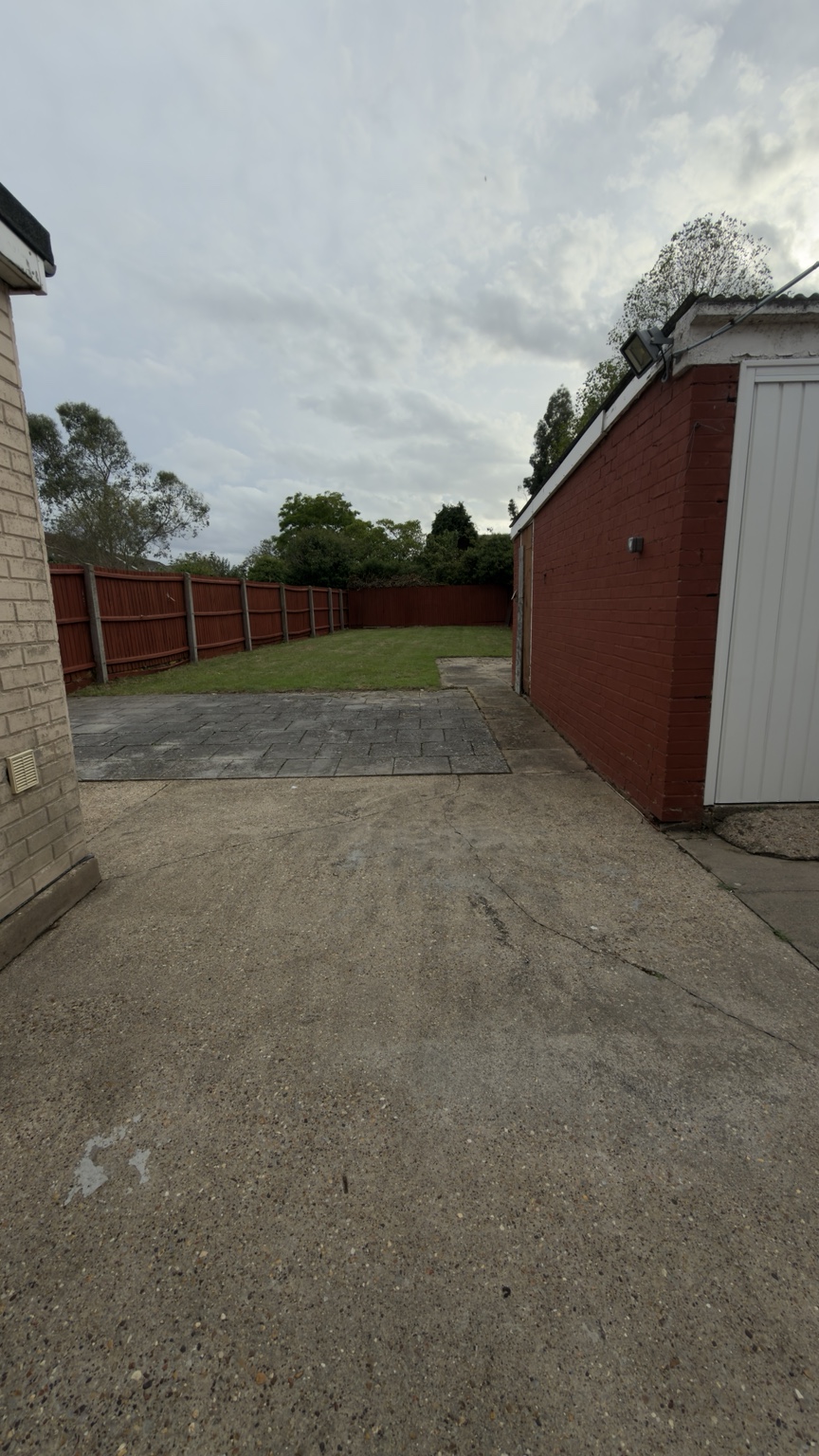 The same garden after, with a green lawn and tidier patio