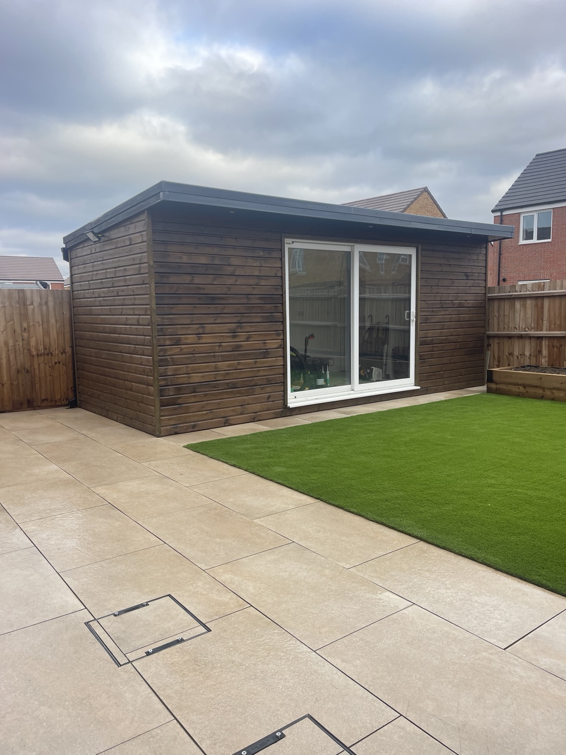 Finished pale stone paving with artificial grass and garden room