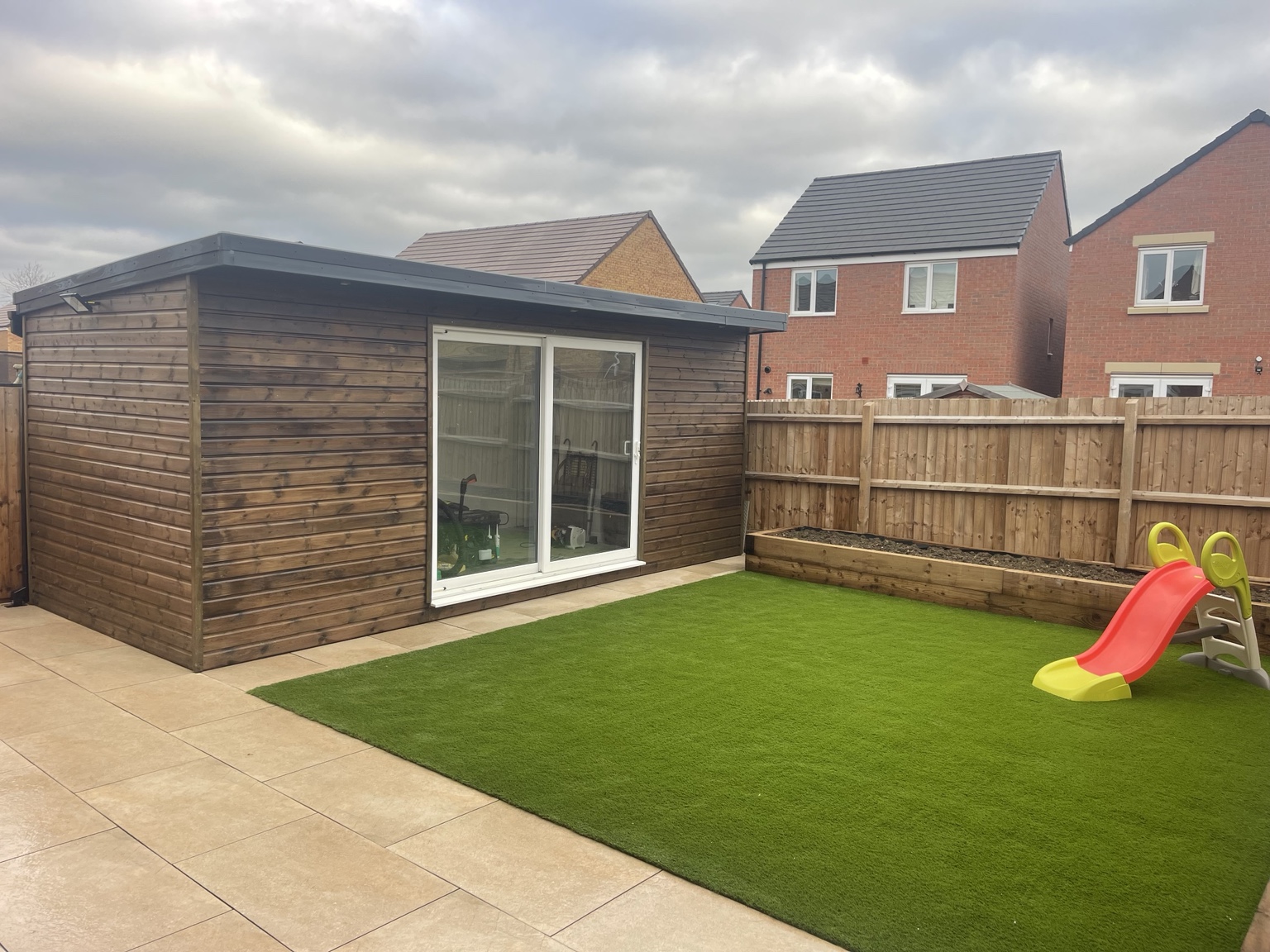 Garden room next to artificial grass and a raised planter