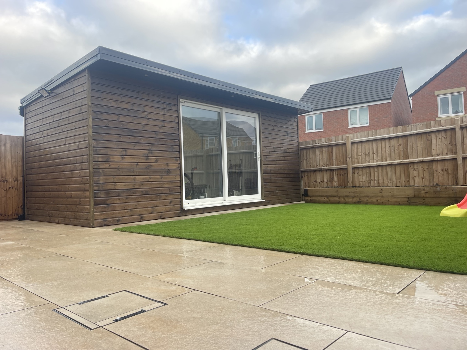 Timber garden room with paved patio and artificial grass