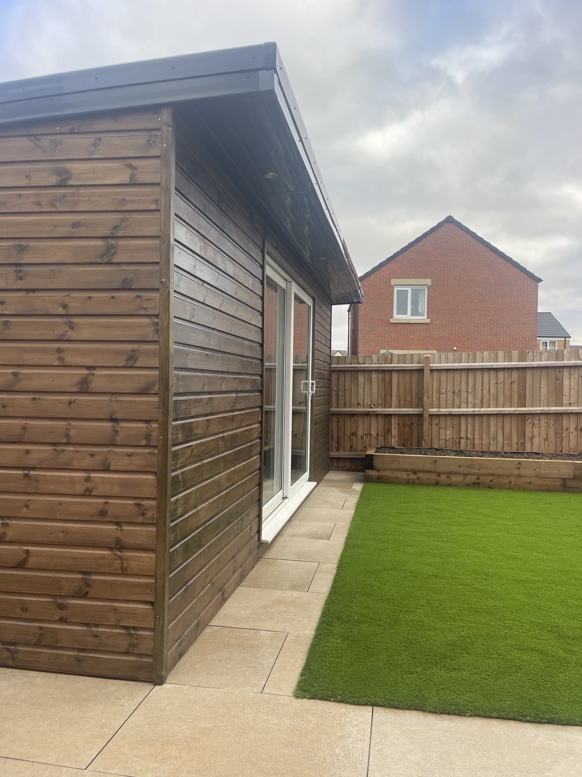 Artificial grass and paving along the garden room
