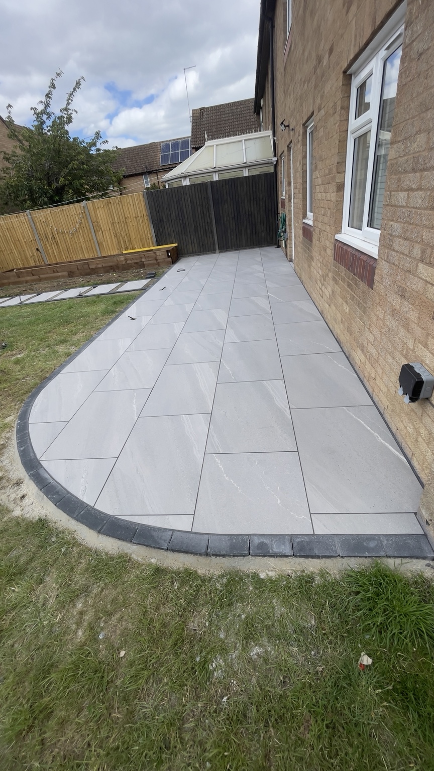 Curved pale stone patio beside a brick house